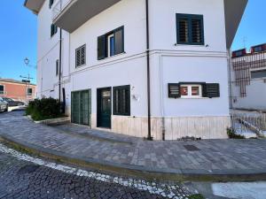 a white building with black shutters on a street at Casa Araiani in Ariano Irpino