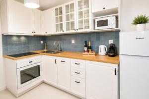 a white kitchen with white cabinets and a sink at La Maya in Caleta De Fuste