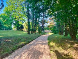 a dirt road in a park with trees and grass at Cocon nature proche Bordeaux in Saint-André-de-Cubzac