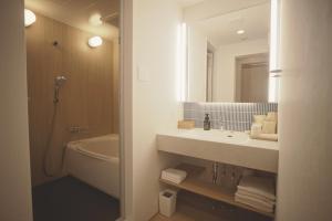 a bathroom with a sink and a tub and a mirror at Amu in Beppu