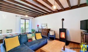 a living room with a blue couch and a tv at Gîte Scopa in Murol +10 photos