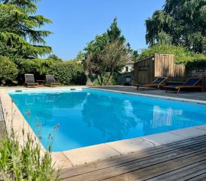 a swimming pool with blue water in a yard at Cocon nature proche Bordeaux in Saint-André-de-Cubzac