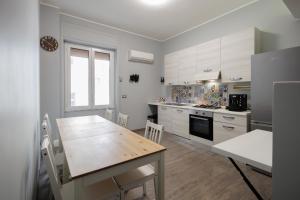 a kitchen with a wooden table and a dining room at La Palazzata Urban Suites in Messina +30 photos
