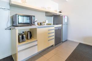 a kitchen with a refrigerator and a microwave at Harbour View Apartment on 11th floor King Bed in Darwin