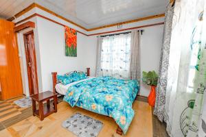 a bedroom with a bed with a blue comforter and a window at Chakruok Gardens, Hawi in Bondo