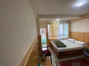 a small bedroom with a bed and a red chair at Tenzin's Inn in Jālāpahār