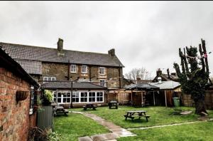 ein großes Backsteingebäude mit einem Picknicktisch im Hof in der Unterkunft The Fox and Maple in Wickwar