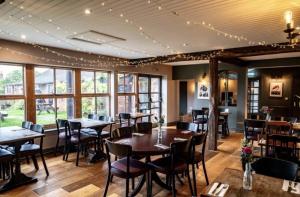 ein Esszimmer mit Tischen, Stühlen und Fenstern in der Unterkunft The Fox and Maple in Wickwar
