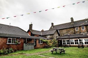 Eine Gruppe von Backsteingebäuden mit einem Picknicktisch im Hof in der Unterkunft The Fox and Maple in Wickwar