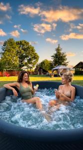 two women sitting in a jacuzzi in a pool at Fotuso House in Majdany Wielkie