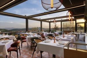 a restaurant with white tables and chairs and large windows at Sheraton Uşak Hotel & Thermal Spa in Uşak