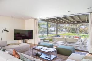 a living room with white furniture and a large window at Majordoms Golf Peralada in Peralada