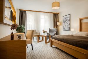 a hotel room with a bed and a desk and chairs at Wellness Hotel Gendorf in Vrchlabí +58 photos
