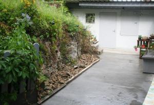 a walkway next to a retaining wall with plants at Ferienwohnung Hexenhäusla in Gößweinstein