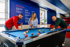 a group of people standing around a pool table at Boutique Hostel Forum in Zadar