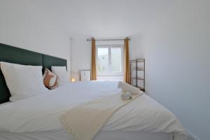 a bedroom with a large white bed with a window at Le petit nid Rémois - Parking - King size in Reims