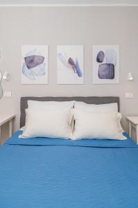 a bed with two white pillows and paintings on the wall at House Rosa in Mali Lošinj