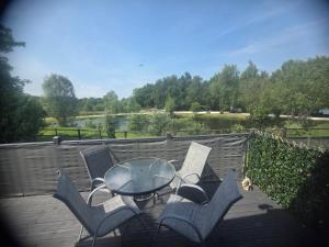 a patio with a glass table and chairs on a deck at JLUX Lodges in Crowle