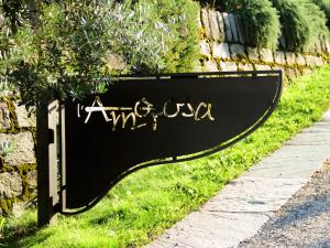 a black sign sitting in the grass next to a wall at Locanda L'Amorosa in Sementina
