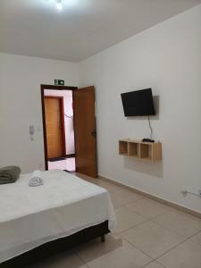 a bedroom with a bed and a tv on the wall at Próximo a UFV 950m, prédio muito tranquilo in Viçosa
