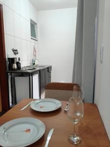 a wooden table with two plates and a wine glass at Próximo a UFV 950m, prédio muito tranquilo in Viçosa