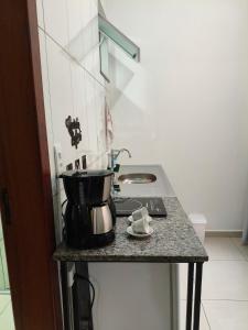 a kitchen counter with a coffee pot on a stove at Próximo a UFV 950m, prédio muito tranquilo in Viçosa +9 photos