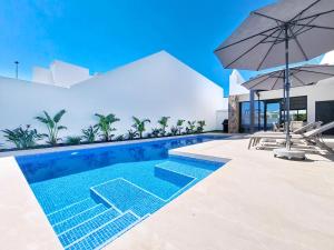 a swimming pool with an umbrella next to a house at Casa Colisa - 8610 in San Javier