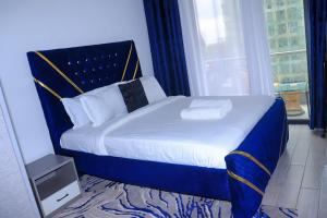a bedroom with a bed with a blue headboard and a window at Malkia Exquisite Homes in Nairobi +6 photos