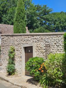 a stone building with a door and some bushes at La forge in Torfou +2 photos