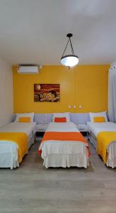 a room with three beds with yellow and orange sheets at Pousada Buona Serata in Bento Gonçalves