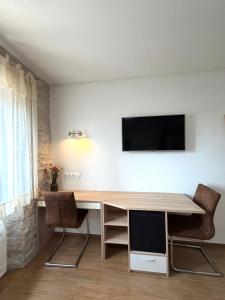 a desk with two chairs and a television on a wall at Tea Rooms II in Bale