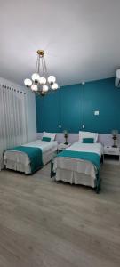 a bedroom with two beds and a chandelier at Pousada Buona Serata in Bento Gonçalves