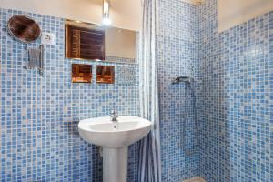 a blue tiled bathroom with a sink and a shower at Buhardilla en centro histórico in Málaga +12 photos