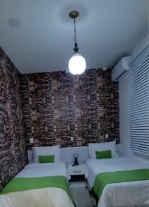 a bedroom with two beds and a brick wall at Pousada Buona Serata in Bento Gonçalves