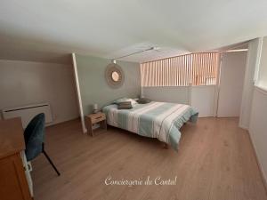a bedroom with a bed and a table and a chair at Edelweiss in Apchon