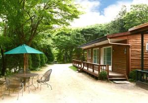 a patio with a table and an umbrella next to a cabin at Pocheon Haneulbat Pension in Pocheon