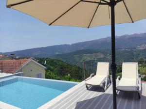 a swimming pool with two chairs and an umbrella at Geres Andorinhas House in Vieira do Minho