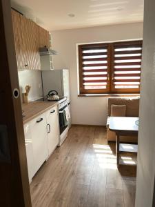 a kitchen with white cabinets and a table and a couch at Na Młace Apartament z widokiem in Witów +3 photos