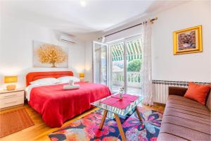 a bedroom with a red bed and a couch at Rooms Nadica in Baška