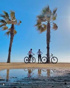 two people with bikes and palm trees on the beach at NEW Family Villa ideal para familias in Pineda de Mar