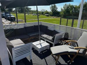 a patio with a couch and chairs and an umbrella at Fenyves Bay Apartman in Balatonfenyves