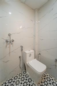 a bathroom with a toilet and a black and white tile floor at palm hotel mansarovar in Jaipur +7 photos
