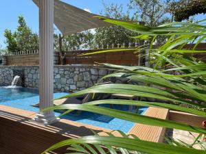 a swimming pool with a wooden deck and plants at Infinity Suites Pushi in Ksamil +32 photos