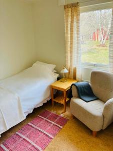 a bedroom with a bed and a chair and a window at Tofta Strand Bed & Breakfast Dubbelrum 93 in Visby