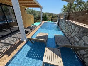 a swimming pool with two chairs and a stone wall at Infinity Suites Pushi in Ksamil