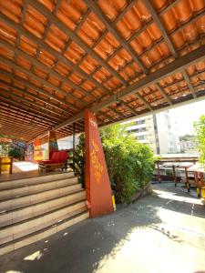 a patio with a wooden roof with tables and benches at RioVermelhopoint in Salvador