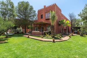 a large brick house with a grass yard at Traditional Villa Dar Izza - 4 suite with breakfast in Douar Soukkane