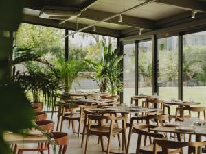 a restaurant with wooden tables and chairs and windows at Hotel Spa Mediterráneo Park in Roses