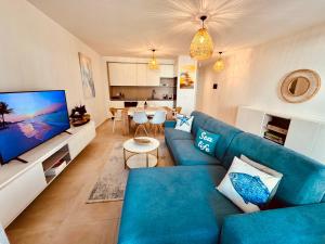 a living room with a blue couch and a tv at San Pietro Premium Meliá Garden Apartment in Lalzit Bay