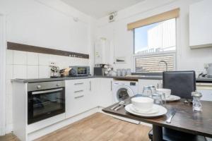 a white kitchen with a table and a dining room at Central Stroud 3-Bedroom Flat with Fast WiFi in Stroud